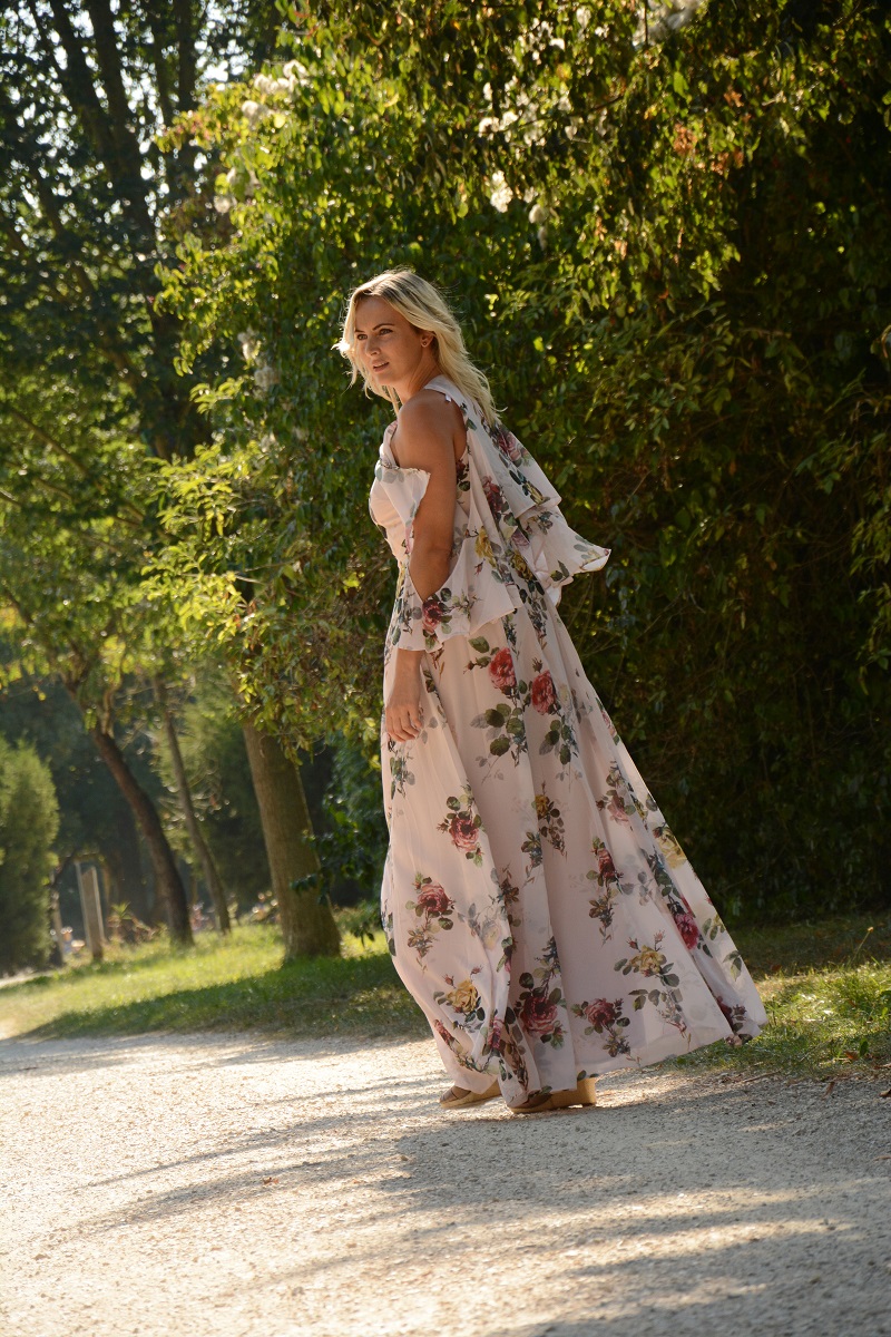 blonde Frau mit langem Blumenkleid geht spazieren